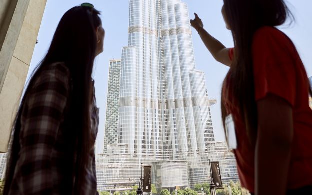 Top view thrill: Tourists savoring Dubai's cityscape from the observation deck, capturing city charm and treasured selfies.